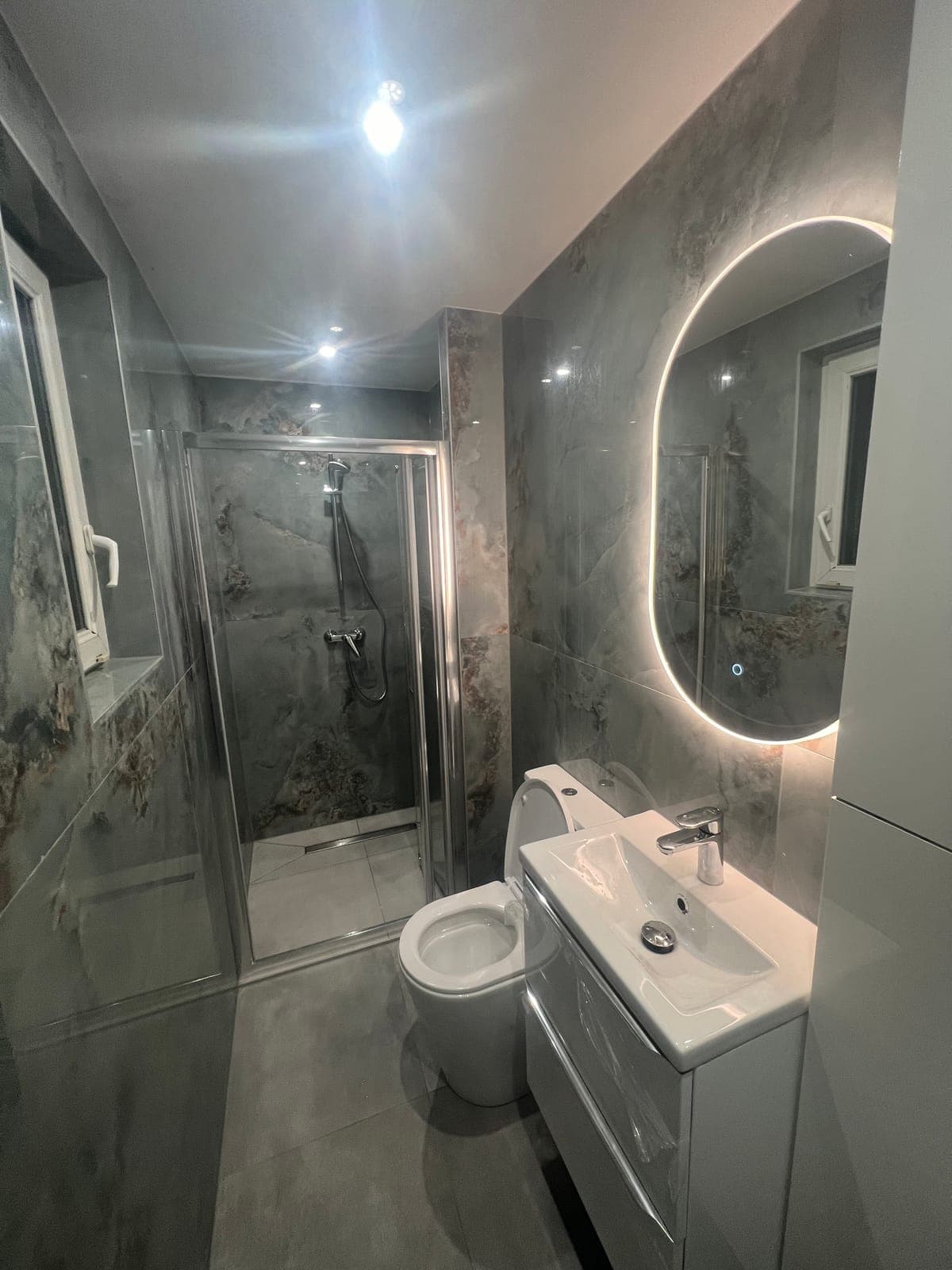 Salle de bain effet marbre gris avec douche et miroir rétroéclairé — réalisation CGM Alsace